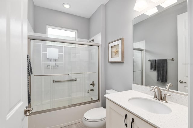 full bathroom featuring toilet, combined bath / shower with glass door, and vanity