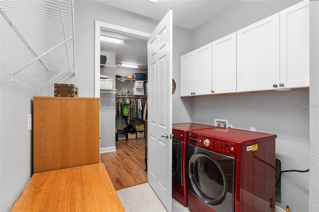 laundry area with cabinets, a textured ceiling, and washing machine and clothes dryer