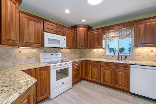 kitchen featuring decorative backsplash, sink, white appliances, light wood-type flooring, and light stone countertops