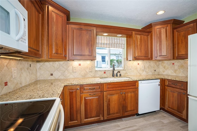 kitchen with decorative backsplash, sink, white appliances, and light stone counters