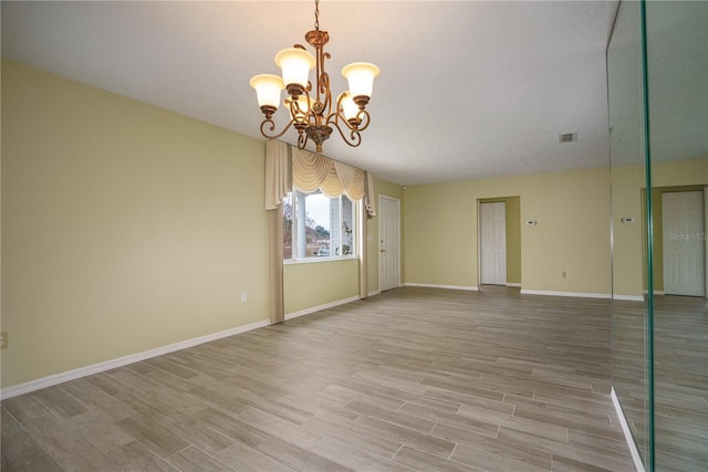 spare room with a notable chandelier and hardwood / wood-style flooring