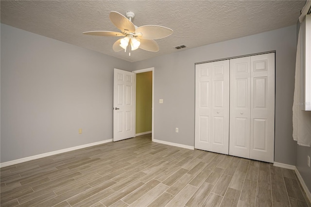 unfurnished bedroom featuring light wood-type flooring, ceiling fan, a closet, and a textured ceiling