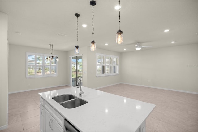 kitchen with decorative light fixtures, white cabinetry, sink, ceiling fan, and a center island with sink