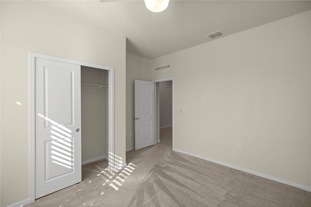 unfurnished bedroom with light carpet, a closet, and a textured ceiling