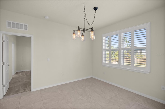 spare room featuring light tile patterned flooring and a chandelier