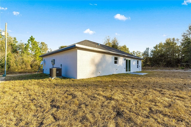 rear view of property featuring cooling unit and a lawn