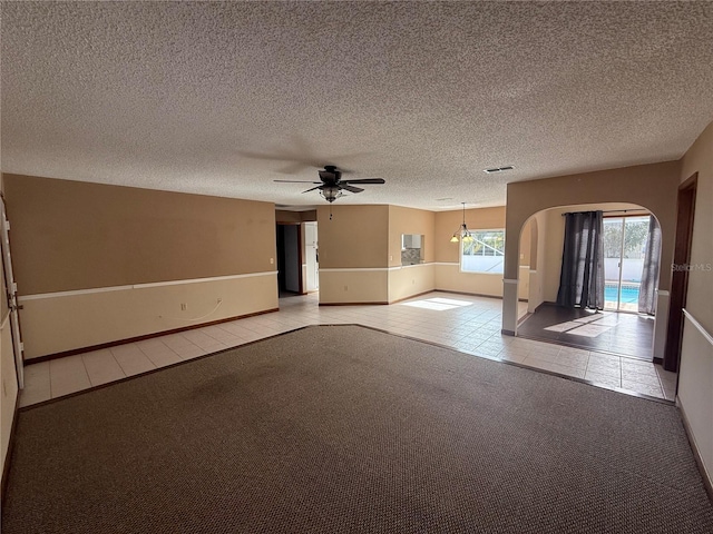 interior space with a textured ceiling, ceiling fan, and light tile patterned floors