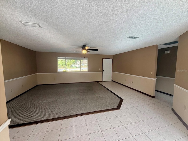 empty room with ceiling fan, light tile patterned floors, visible vents, and baseboards