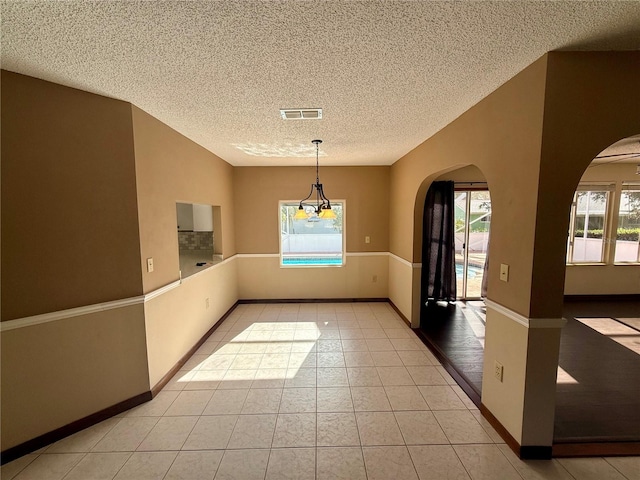 unfurnished dining area featuring light tile patterned floors, plenty of natural light, and arched walkways