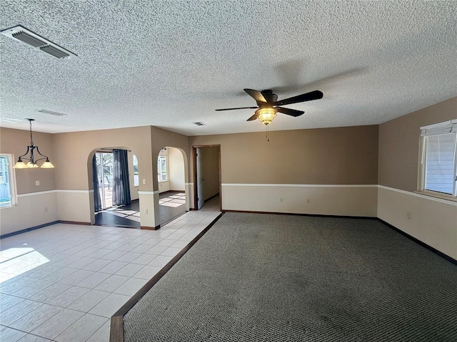 interior space with light tile patterned floors, visible vents, arched walkways, and a textured ceiling