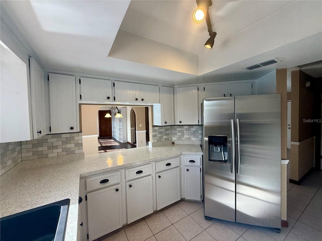 kitchen with a sink, visible vents, decorative backsplash, stainless steel fridge, and a raised ceiling