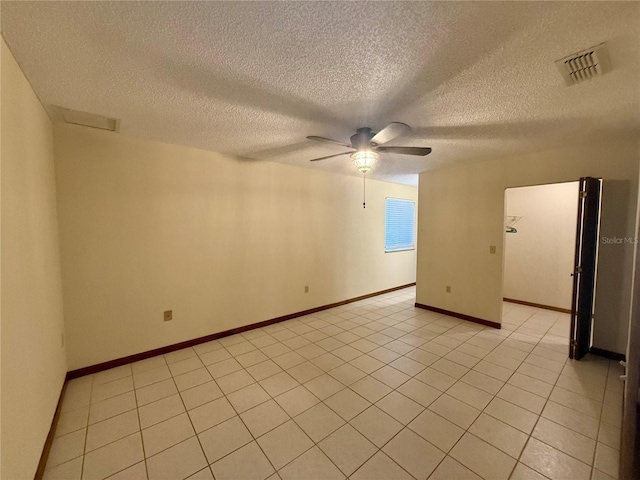 spare room with a ceiling fan, visible vents, a textured ceiling, and baseboards