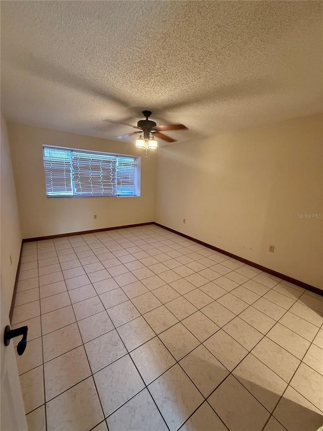 empty room with ceiling fan, a textured ceiling, and baseboards