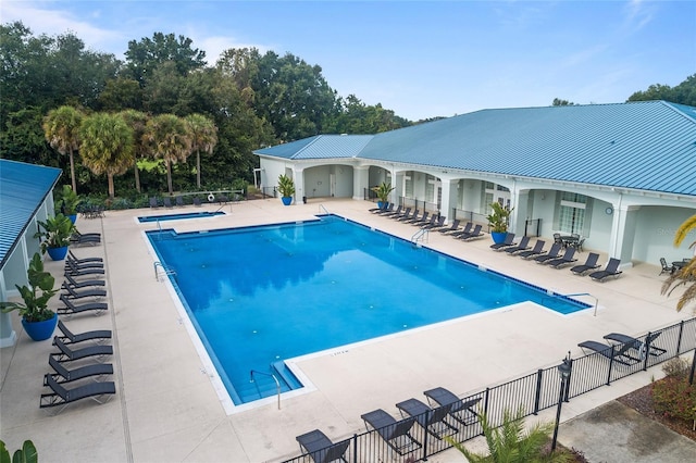 community pool with a patio and fence