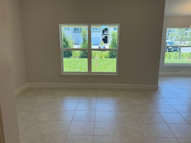 unfurnished room with baseboards, light tile patterned floors, and a healthy amount of sunlight
