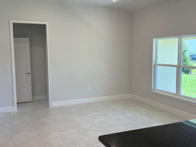 spare room with baseboards and light tile patterned floors