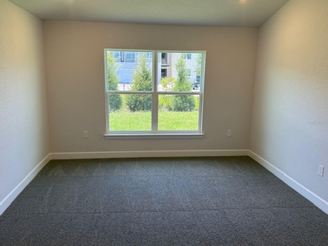 spare room with dark colored carpet and baseboards