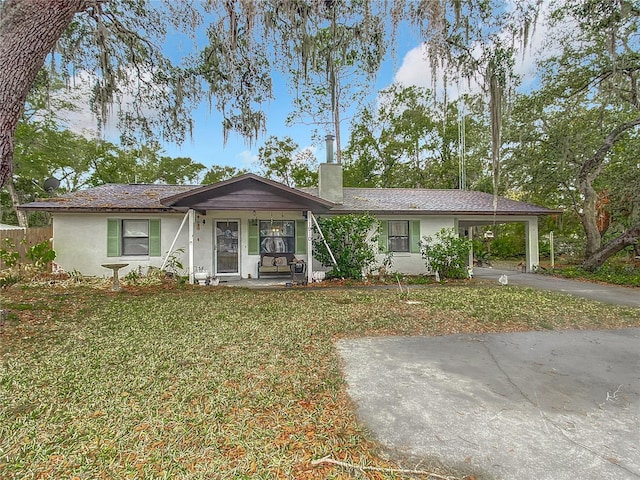 ranch-style house featuring covered porch, a front lawn, and a carport