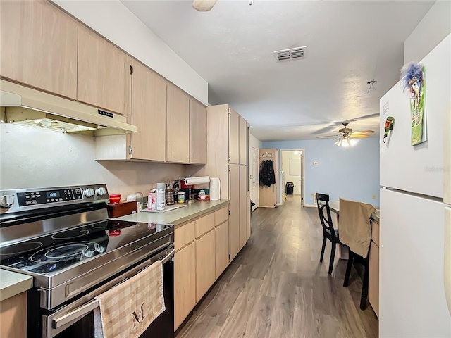 kitchen featuring stainless steel range with electric cooktop, light brown cabinets, white fridge, and light hardwood / wood-style floors