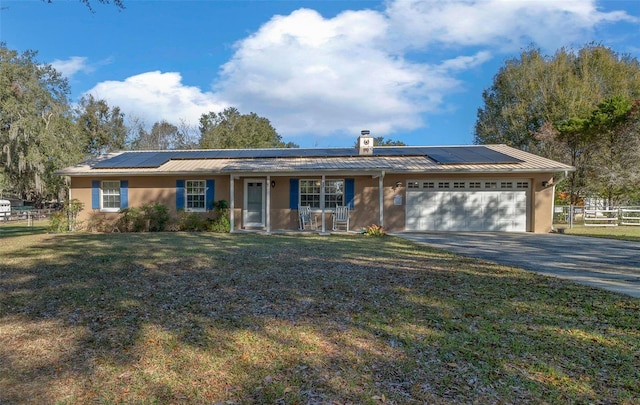 ranch-style home featuring a garage, a front yard, covered porch, and solar panels