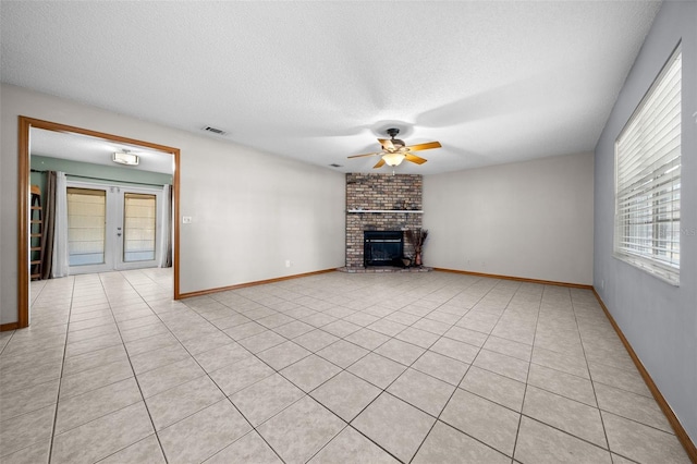 unfurnished living room featuring french doors, a textured ceiling, light tile patterned floors, ceiling fan, and a fireplace