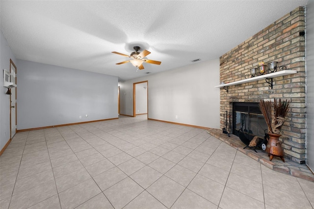 unfurnished living room with ceiling fan, a brick fireplace, a textured ceiling, and light tile patterned floors