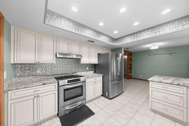 kitchen featuring light tile patterned floors, stainless steel appliances, tasteful backsplash, a tray ceiling, and light stone countertops