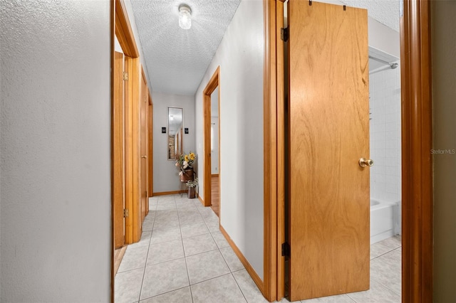 hallway with light tile patterned flooring and a textured ceiling