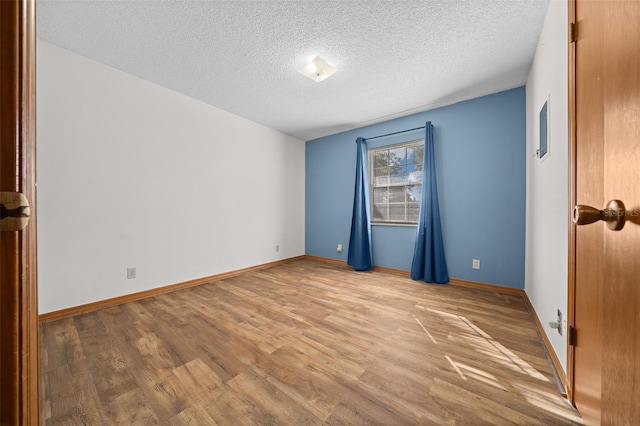 spare room featuring light hardwood / wood-style floors and a textured ceiling