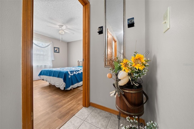 tiled bedroom featuring ceiling fan and a textured ceiling