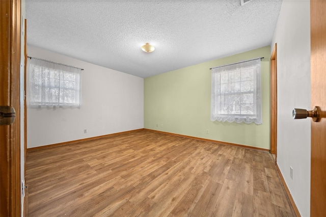 spare room with a textured ceiling and light wood-type flooring