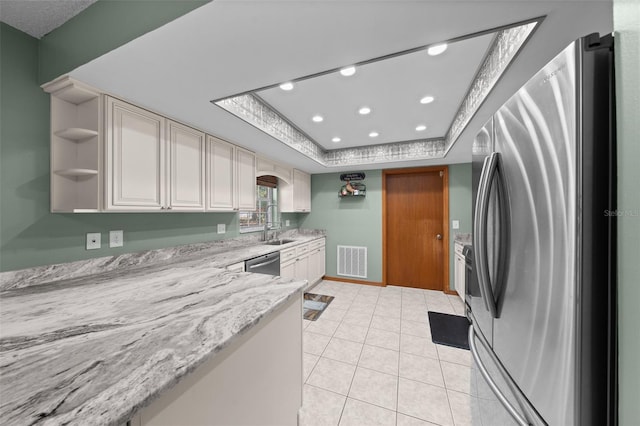 kitchen featuring light tile patterned floors, sink, stainless steel appliances, light stone counters, and a tray ceiling