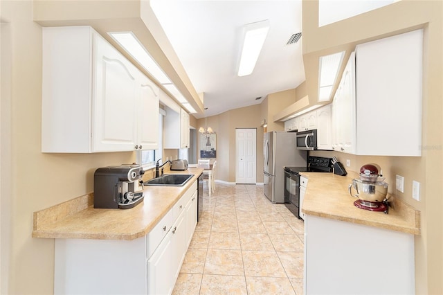 kitchen with vaulted ceiling, sink, light tile patterned flooring, appliances with stainless steel finishes, and white cabinets