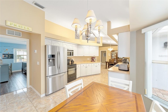 kitchen with stainless steel appliances, white cabinets, decorative light fixtures, and a notable chandelier