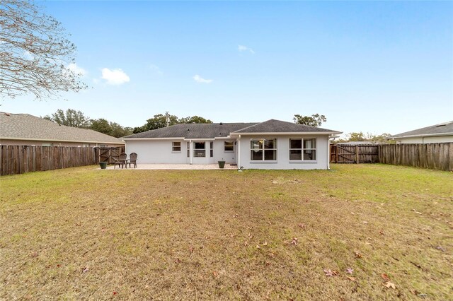 rear view of property featuring a patio and a yard