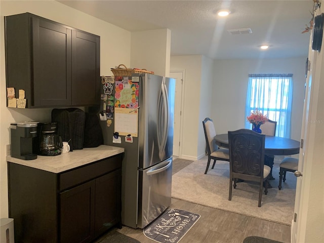 kitchen with stainless steel refrigerator, dark brown cabinetry, and light wood-type flooring