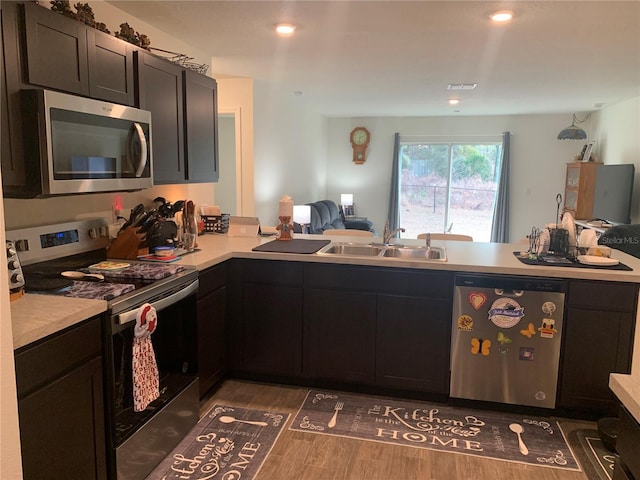 kitchen with dark hardwood / wood-style flooring, sink, stainless steel appliances, and kitchen peninsula