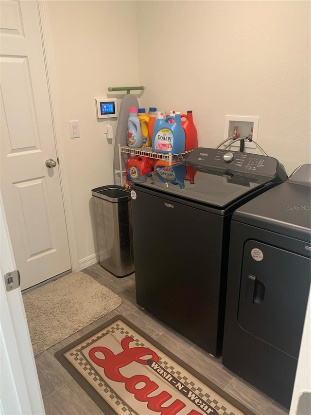 clothes washing area with washing machine and clothes dryer and light hardwood / wood-style floors