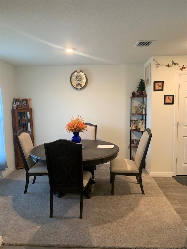 dining area with dark hardwood / wood-style flooring and a textured ceiling