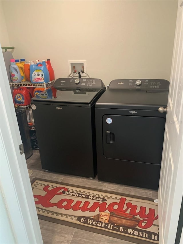 clothes washing area with hardwood / wood-style flooring and washer and clothes dryer