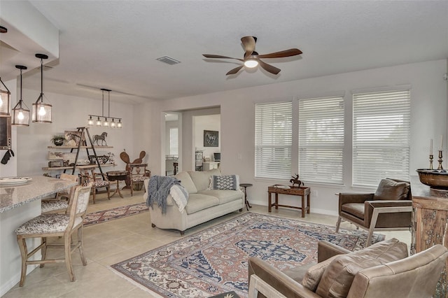 living room featuring a textured ceiling, ceiling fan, and light tile patterned floors