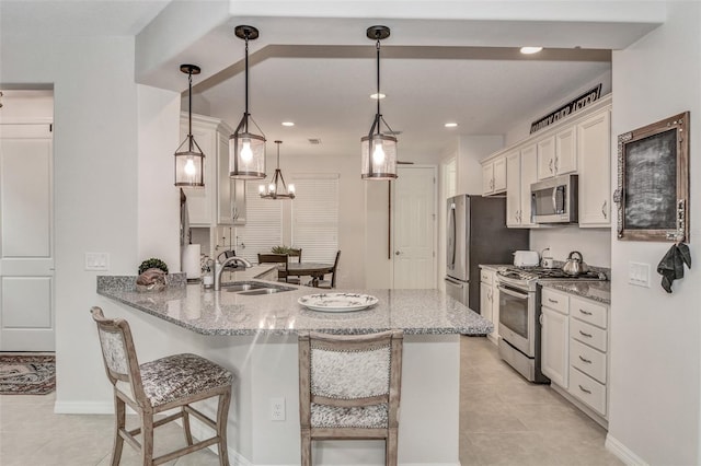 kitchen featuring pendant lighting, a breakfast bar, kitchen peninsula, sink, and appliances with stainless steel finishes