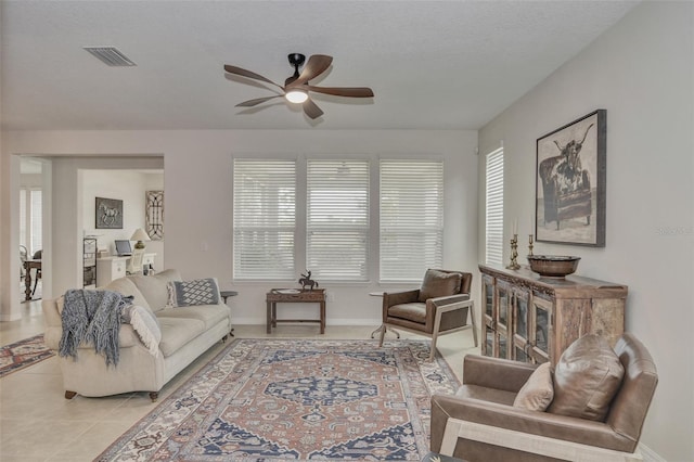 tiled living room with ceiling fan, plenty of natural light, and a textured ceiling