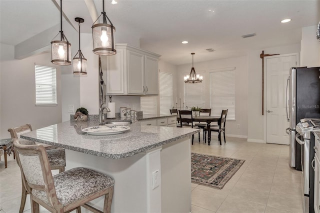 kitchen featuring decorative light fixtures, stainless steel appliances, sink, a kitchen breakfast bar, and light tile patterned floors