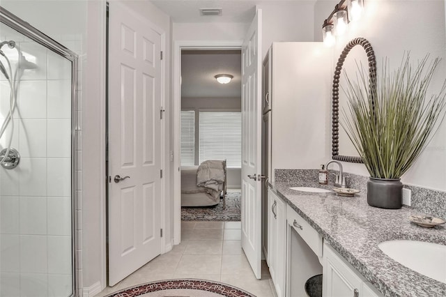 bathroom with a shower with shower door, vanity, and tile patterned flooring