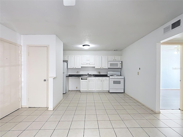 kitchen with light tile patterned flooring, white cabinetry, sink, and white appliances