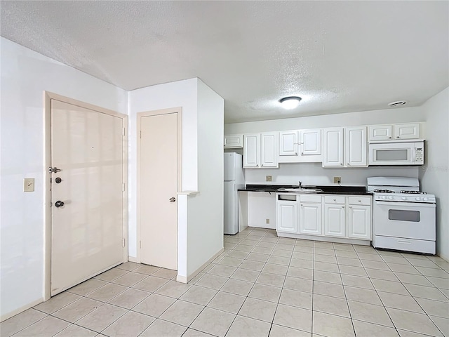 kitchen featuring sink, light tile patterned flooring, white appliances, white cabinetry, and a textured ceiling