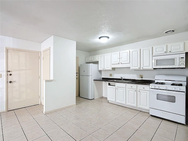 kitchen with white appliances, white cabinets, a textured ceiling, sink, and light tile patterned floors