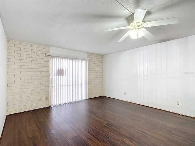 spare room with ceiling fan, dark hardwood / wood-style flooring, brick wall, and a textured ceiling