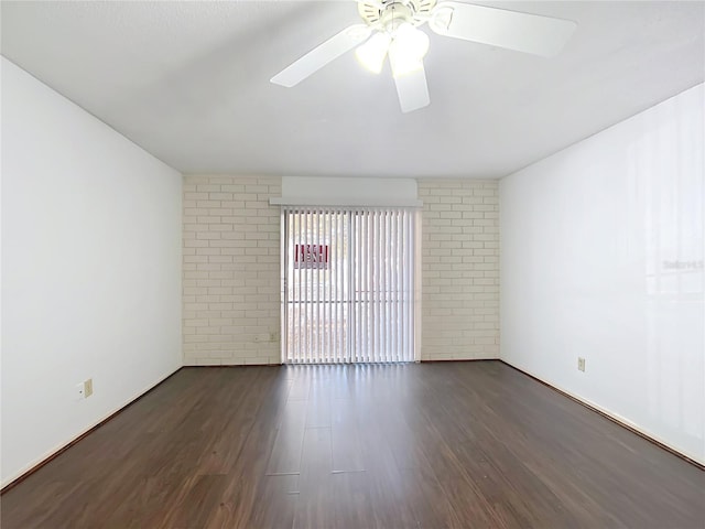 empty room featuring ceiling fan, dark wood-type flooring, and brick wall